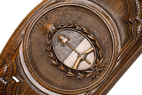 Detail view of the hand-carved Argentine Republic crest on solid wood.
