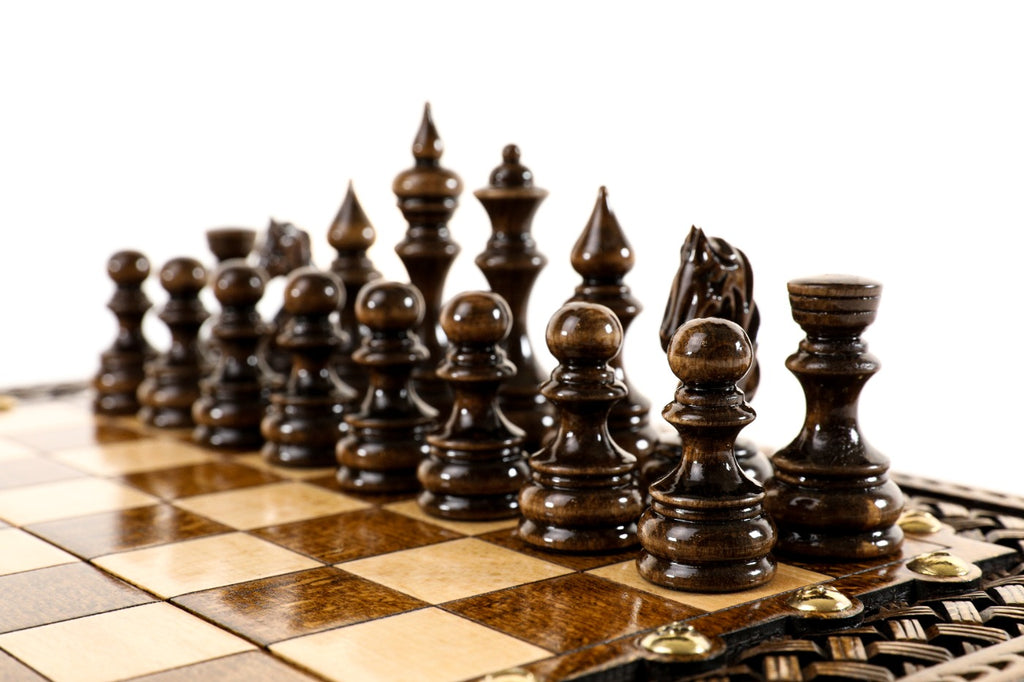 Dark hand-carved chess pieces on the beech and walnut squares of the braid chess board