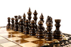 Dark hand-carved chess pieces on the beech and walnut squares of the braid chess board