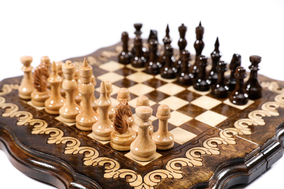Small handmade chess board with two-tone ornament border and wooden pieces, close angle