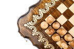 Scalloped corner of the travel chess board with pale ornament and light pieces