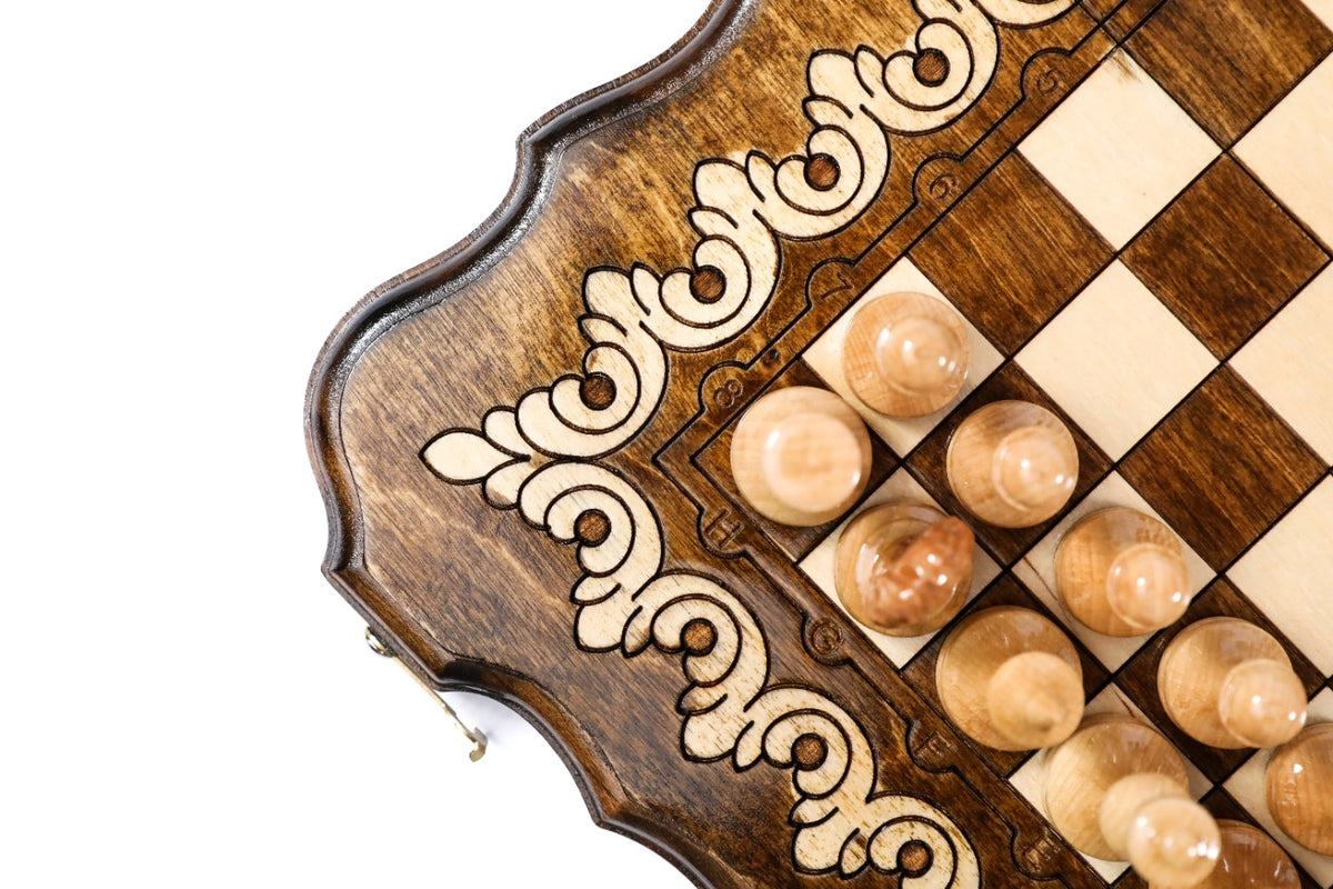 Scalloped corner of the travel chess board with pale ornament and light pieces