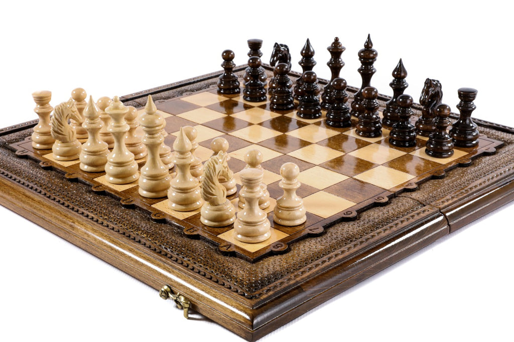 Handmade wooden chess board with carved border and hand-carved pieces, angled view