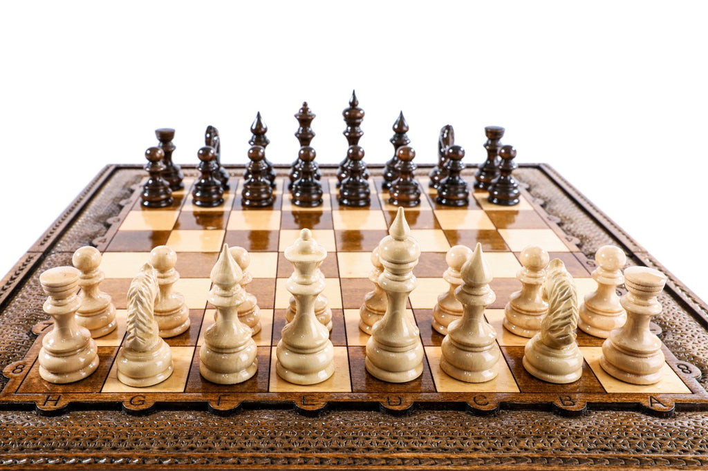 Hand-carved light wood chess pieces in the front rank of the wooden chess board