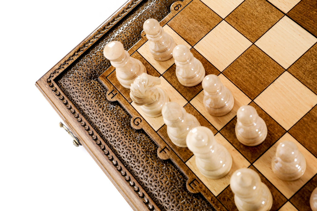 Light hand-carved chess pieces against the carved frame of the wooden board