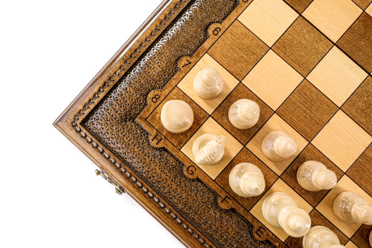 Close view of light chess pieces and the carved ornament border of the chess board