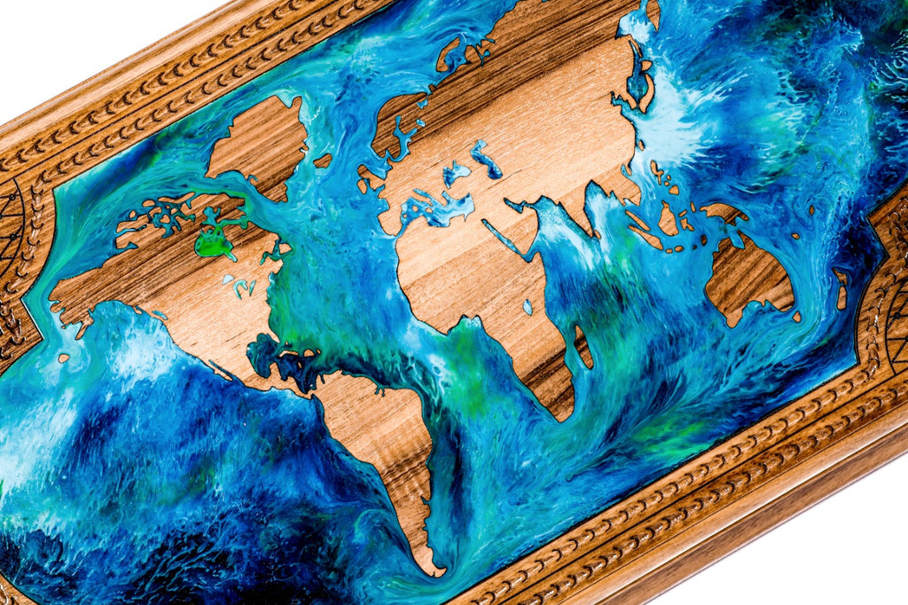 Close-up of the world map: walnut continents standing in swirling blue, turquoise and green epoxy