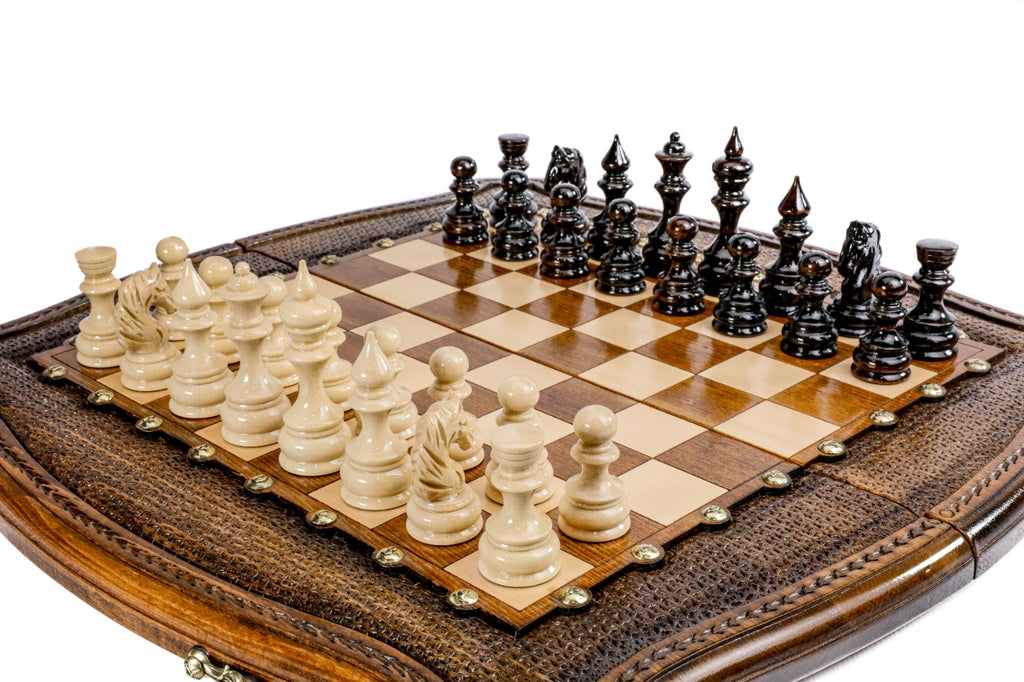 Hand-carved chess board with contour outline, textured frame, bronze studs and carved pieces, close angle