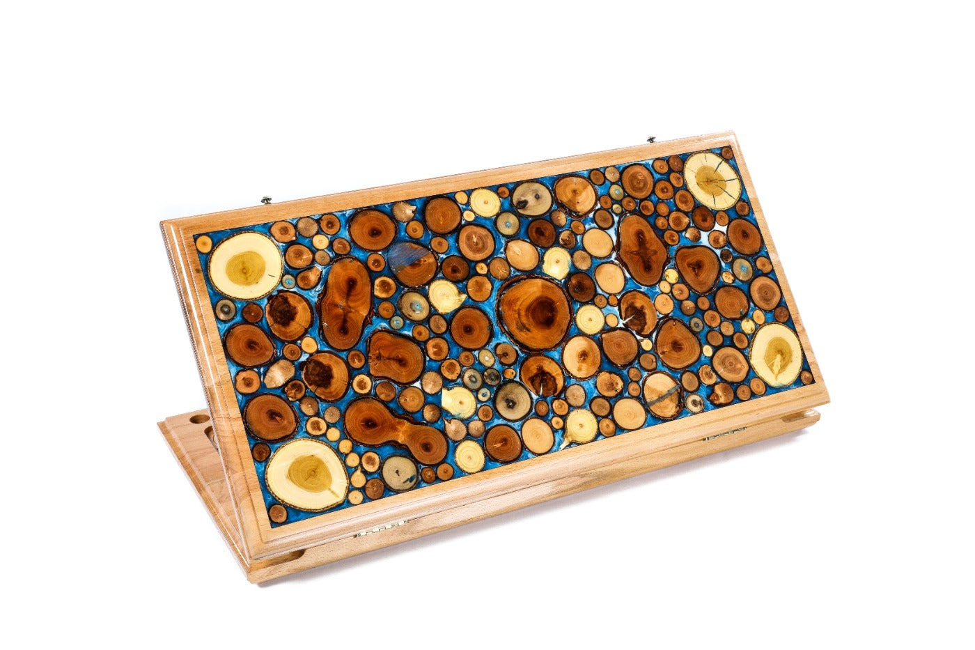 A frontal shot of the closed backgammon board showing the unique tree branch slices suspended in translucent blue epoxy resin.