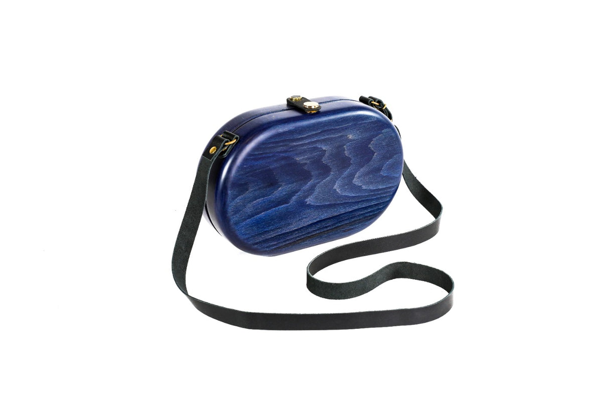 Navy blue oval wooden bag with leather strap — side view