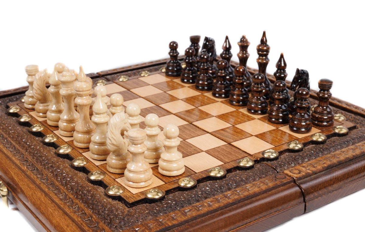 Small handmade chess board with carved textured border and hand-carved wooden pieces, close angle