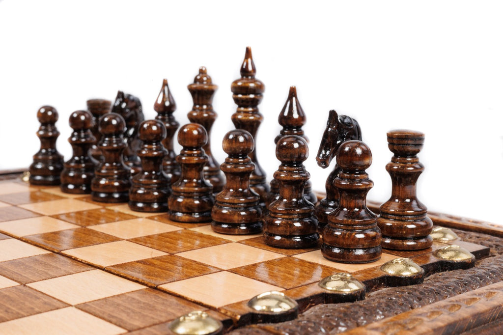 Dark hand-carved chess pieces on the beech and walnut squares of the travel board