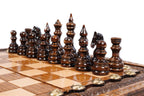 Dark hand-carved chess pieces on the beech and walnut squares of the travel board