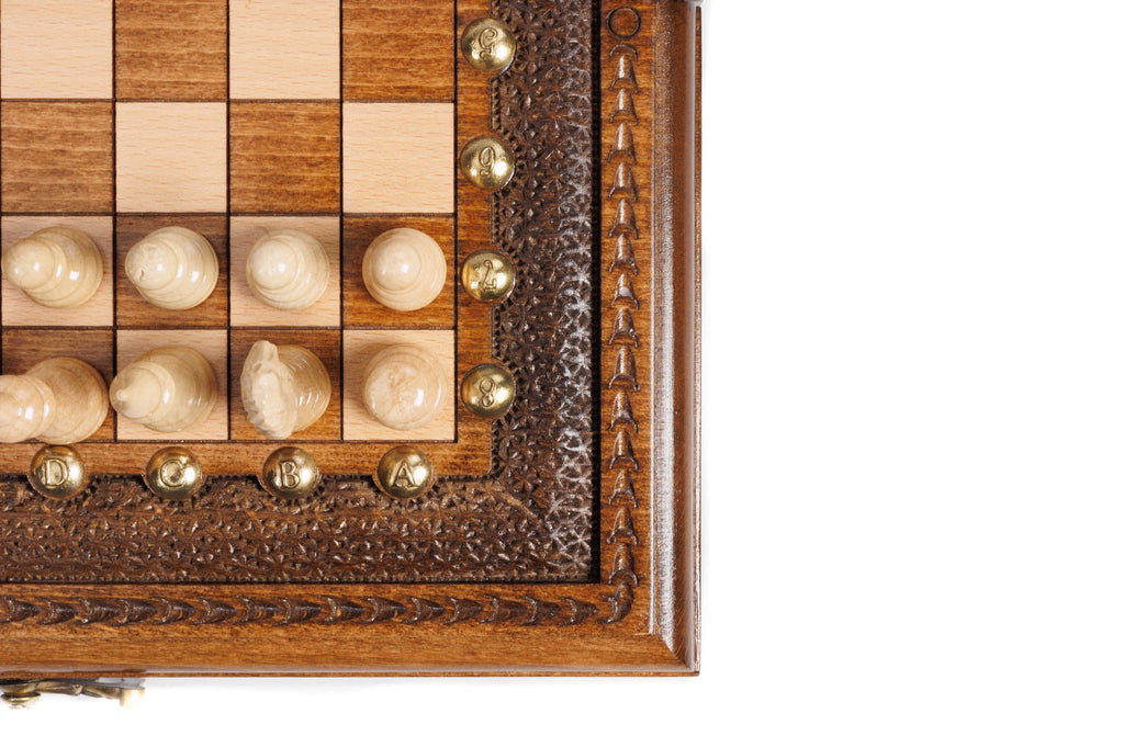 Corner detail of the carved frame, bronze studs and light chess pieces