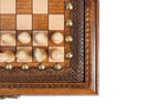 Corner detail of the carved frame, bronze studs and light chess pieces