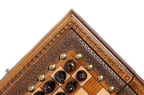 Corner of the carved wooden frame with dark chess pieces and bronze studs