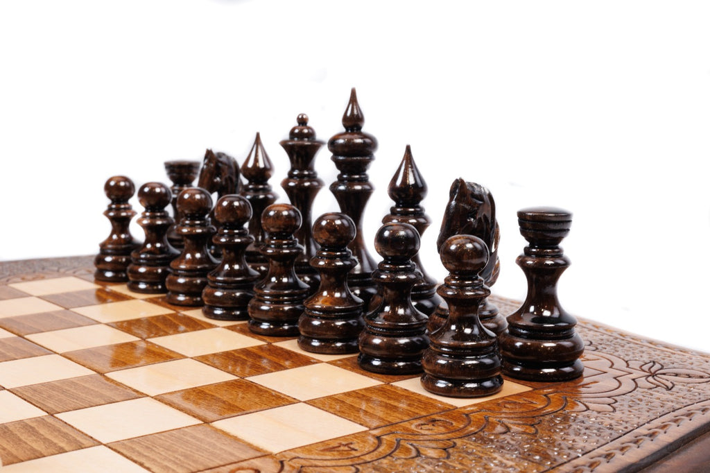 Dark hand-carved chess pieces on the beech and walnut squares of the contour board