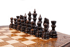 Dark hand-carved chess pieces on the beech and walnut squares of the contour board