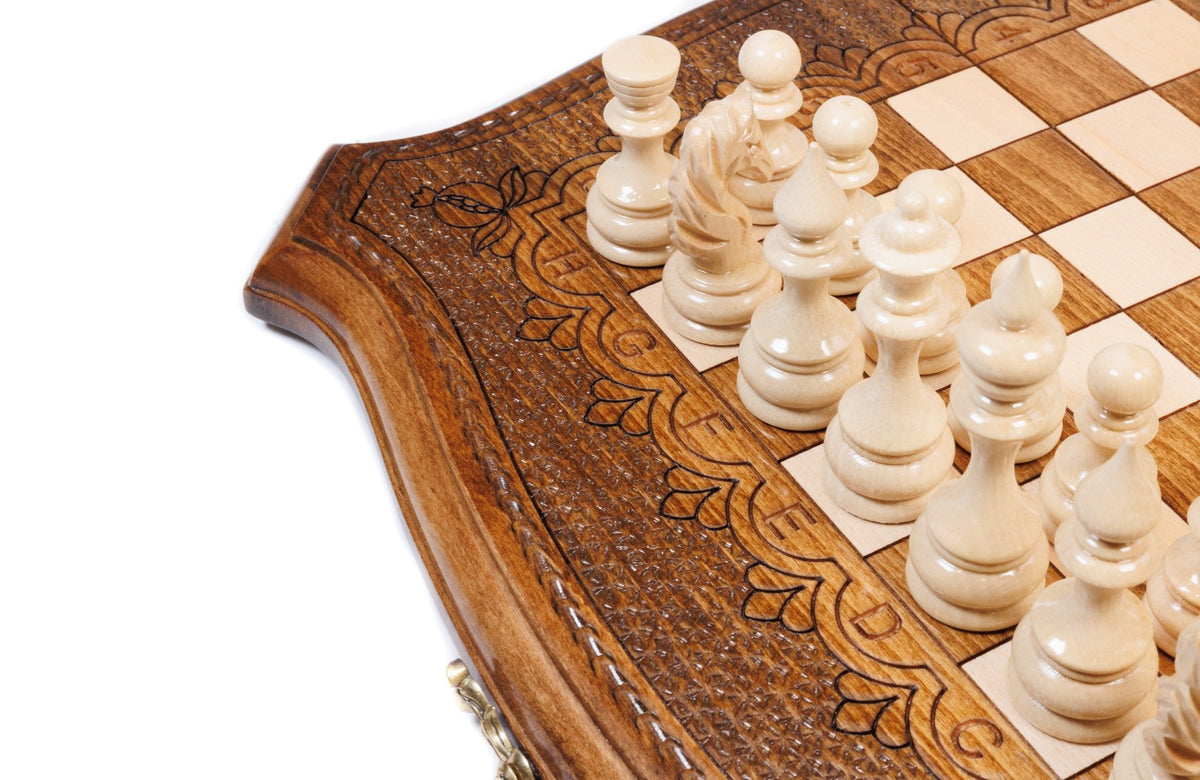Light hand-carved chess pieces beside the carved scroll ornament of the contour frame