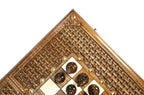 Corner of the walnut board with open braid frame and dark chess pieces on the epoxy field