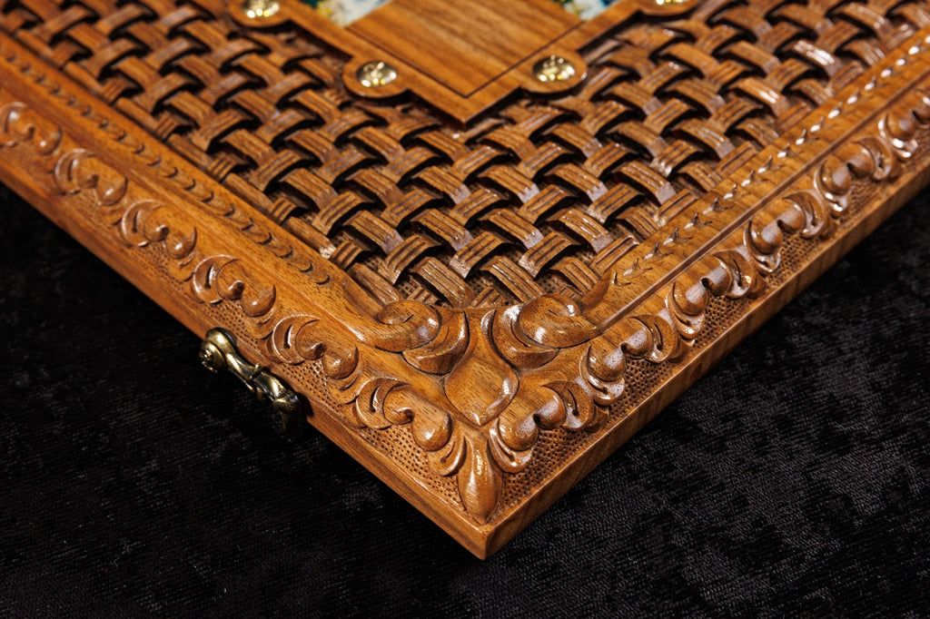 Close-up of a wooden box with intricate carvings and gold accents on a dark background