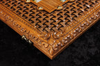 Close-up of a wooden box with intricate carvings and gold accents on a dark background