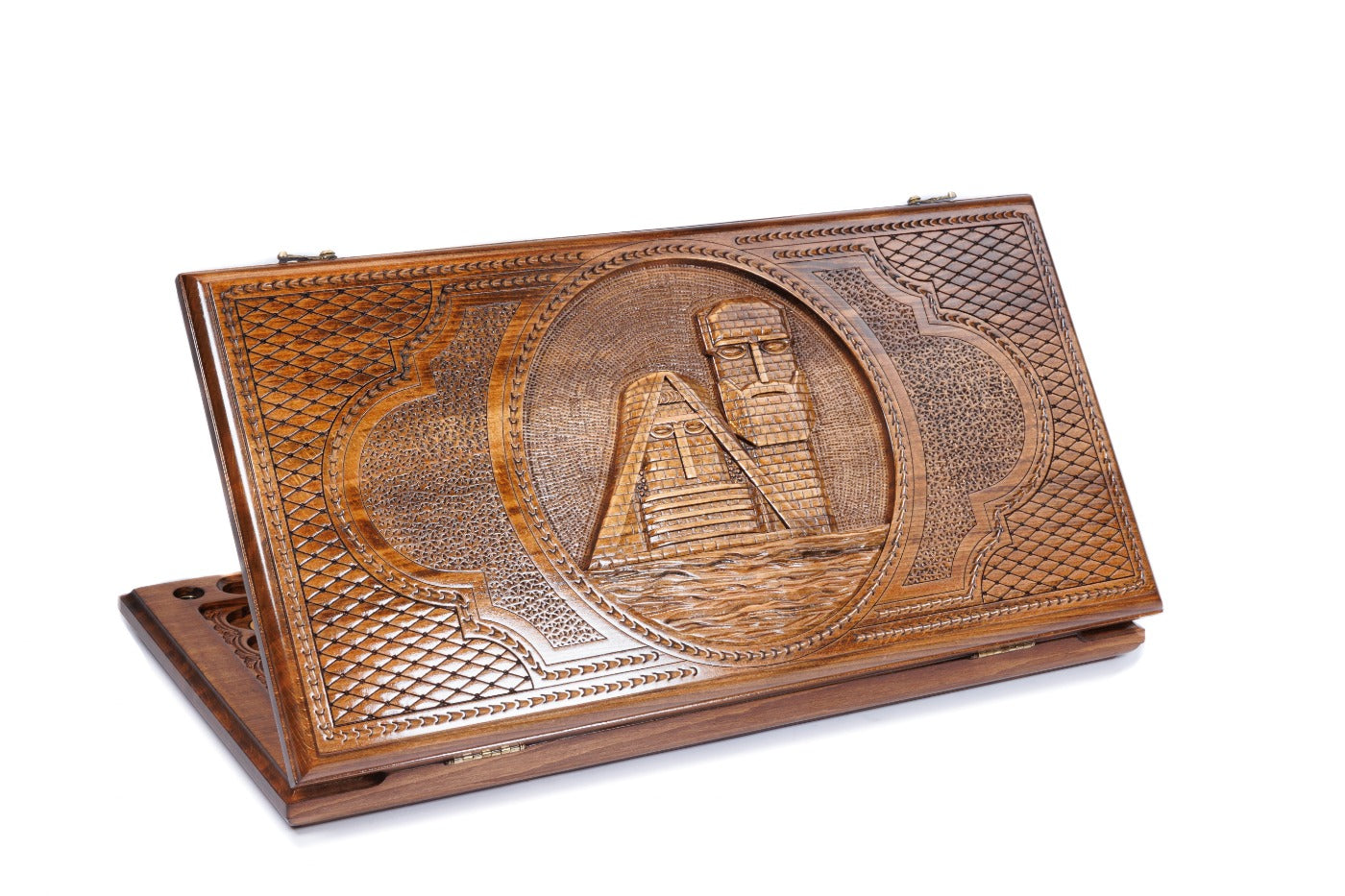 A wide shot of the closed wooden backgammon board showing the detailed Gandzasar Monastery carving on the dark wood exterior.