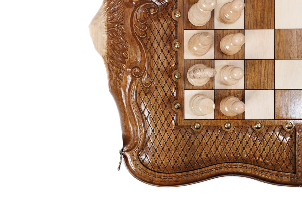 Light hand-carved chess pieces beside the carved braid border and scrollwork of the walnut board