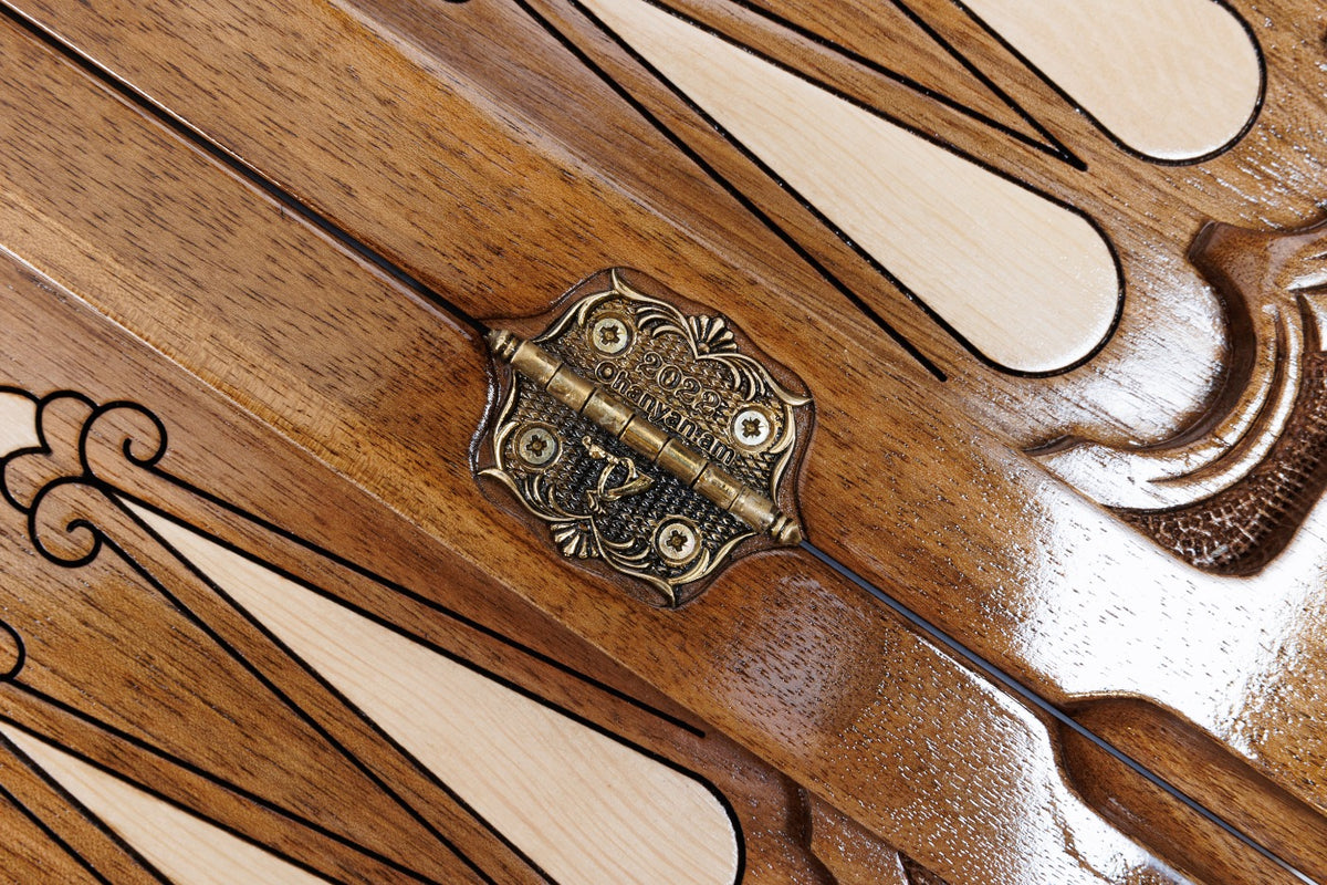 Ornate cast-bronze hinge on the carved walnut backgammon field