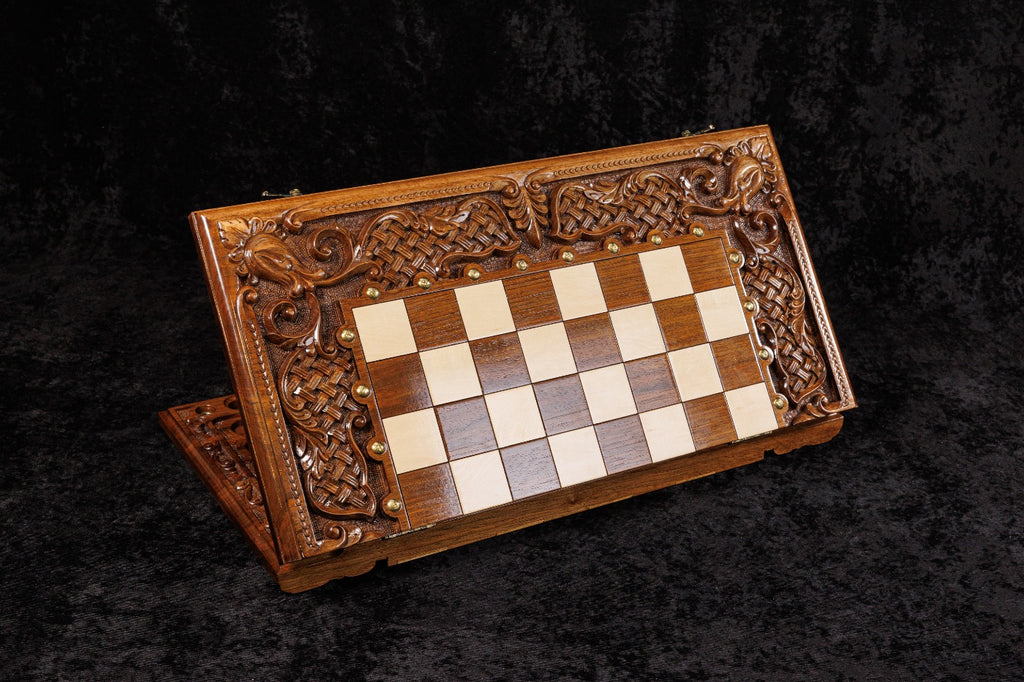 Wooden chessboard with intricate carvings on a dark background