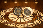 Two ornament checkers with cast emblems, bronze-toned and silver-toned, on the hornbeam wheel inlay