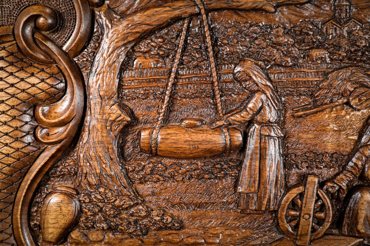 Woman at the spinning wheel beside the house, carved in deep relief, close-up