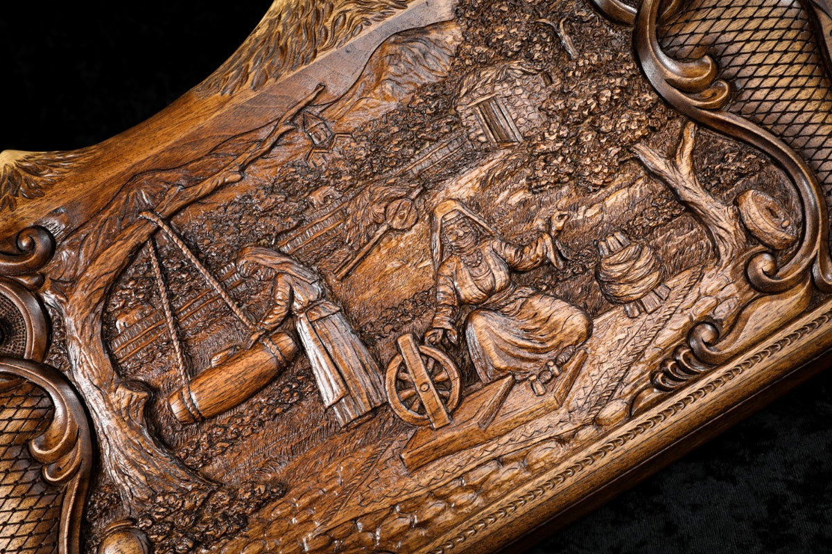 Close-up of the village scene: woman at the spinning wheel and the butter churn on its tree, carved in deep relief