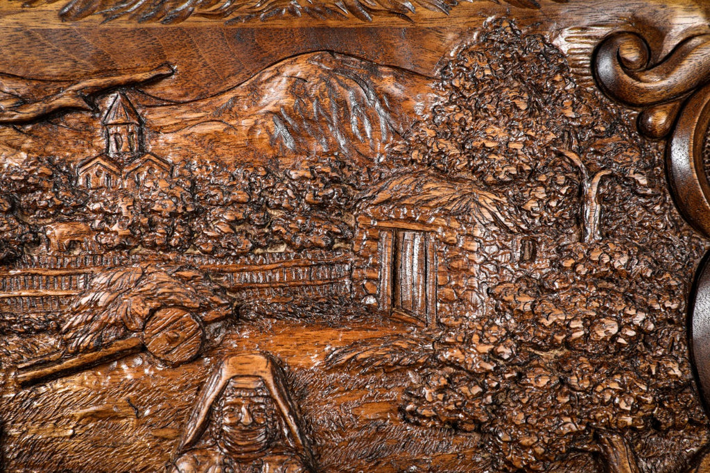 Village church, houses and orchards carved in deep relief on the walnut lid, close-up