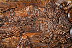Village church, houses and orchards carved in deep relief on the walnut lid, close-up