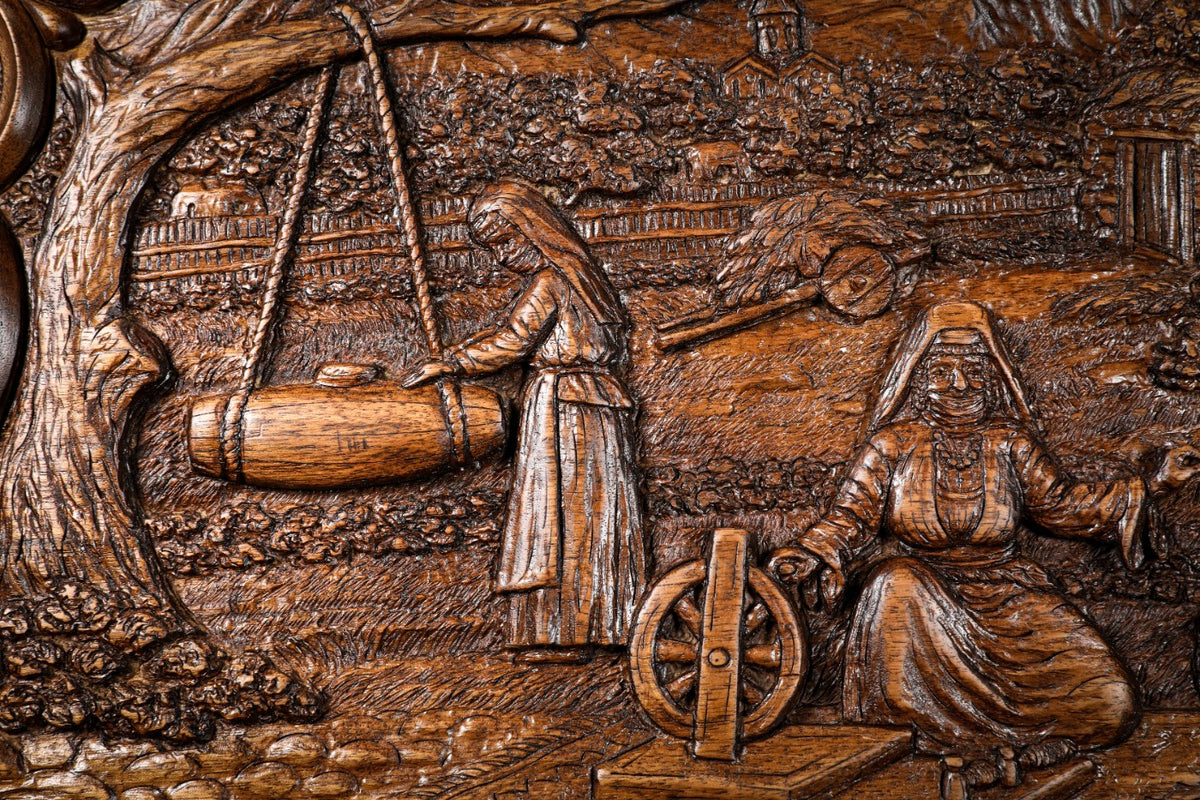 Butter churn hanging from the tree beside the seated woman, carved in deep relief, close-up