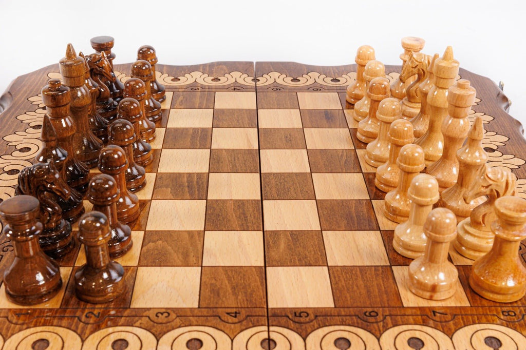 Wooden chessboard with brown and beige chess pieces on a white background