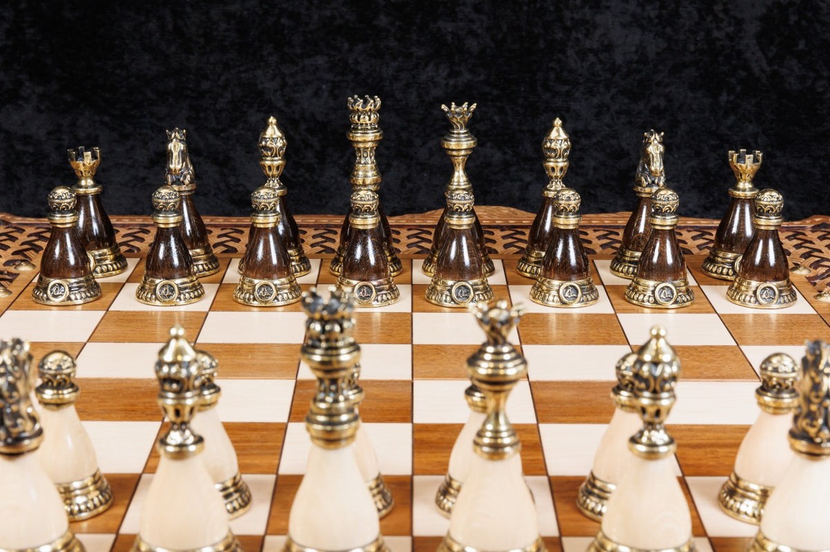 Bronze chess pieces on cream and dark bases lined up on the chessboard, close-up