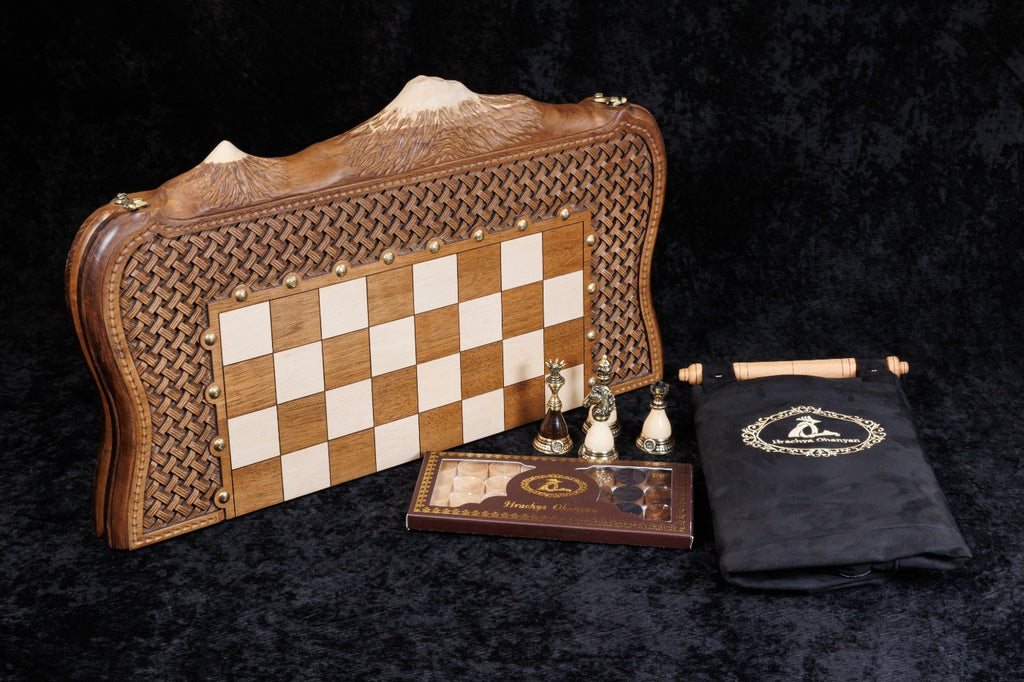 Chess and backgammon set closed beside the bronze pieces, checkers box and black carrying case