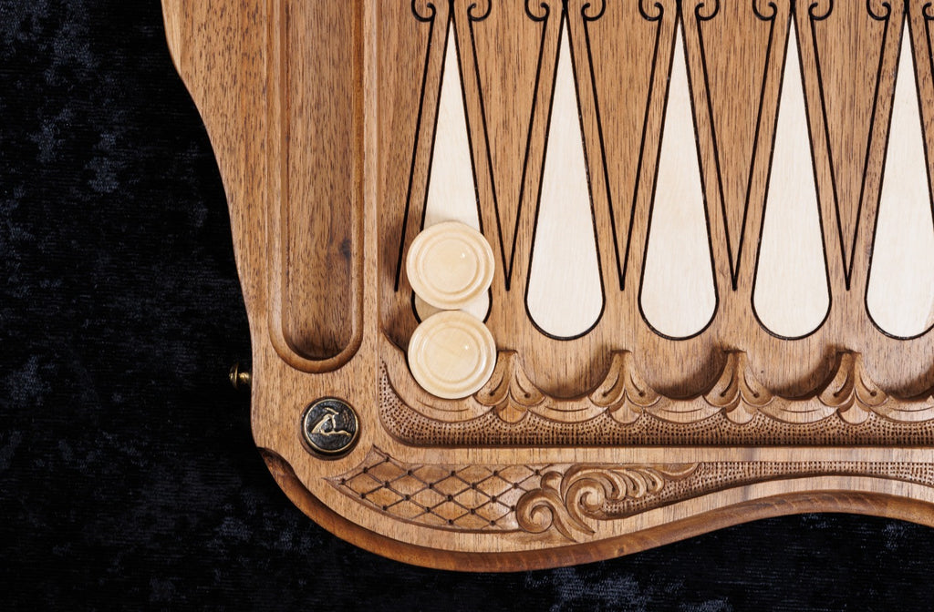 Hornbeam-inlaid points and checkers on the open backgammon board, bronze stud at the corner