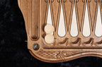 Hornbeam-inlaid points and checkers on the open backgammon board, bronze stud at the corner