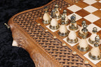 Bronze chess pieces set up on the chessboard with the carved live edge in front