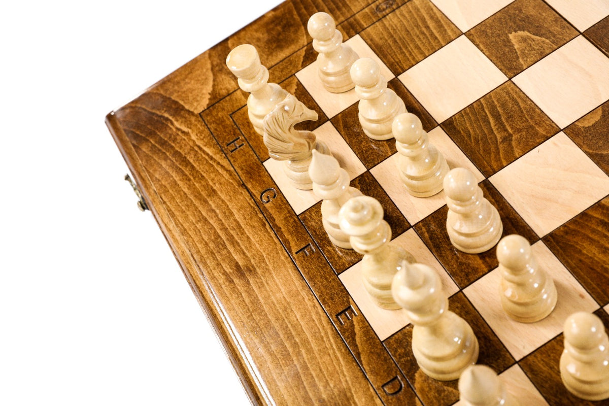 Light hand-carved chess pieces on the beech and walnut squares beside the carved letters