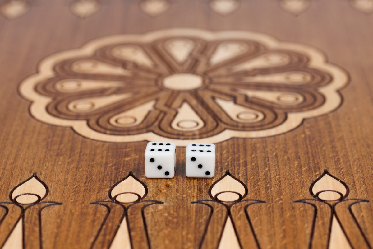 Eight-petal wheel ornament with two dice on the dark field of the open backgammon board