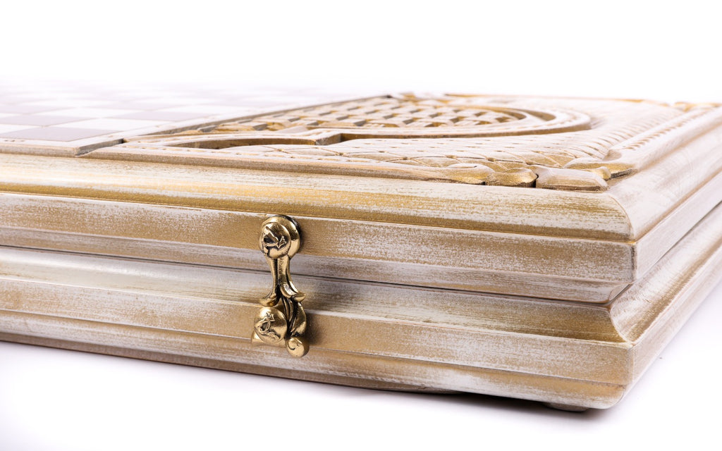Closed white and gold backgammon board from the edge, cast-bronze clasp and layered lid