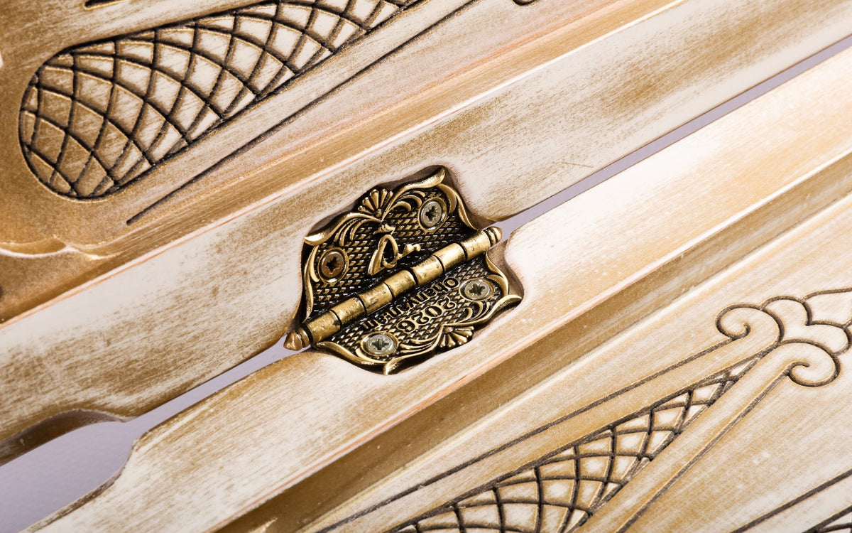 Ornate cast-bronze hinge on the white and gold backgammon board with lattice carving beside it
