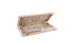 White and gold backgammon board opened flat, pale points drawn in line, petal wheel on each half