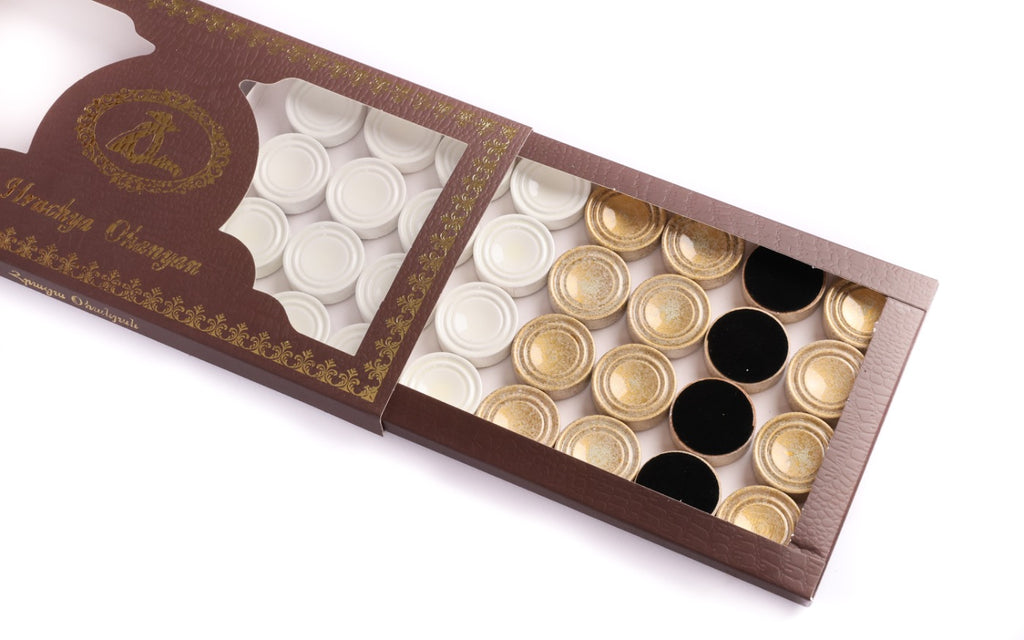 White and gold checkers of the backgammon set in the branded box