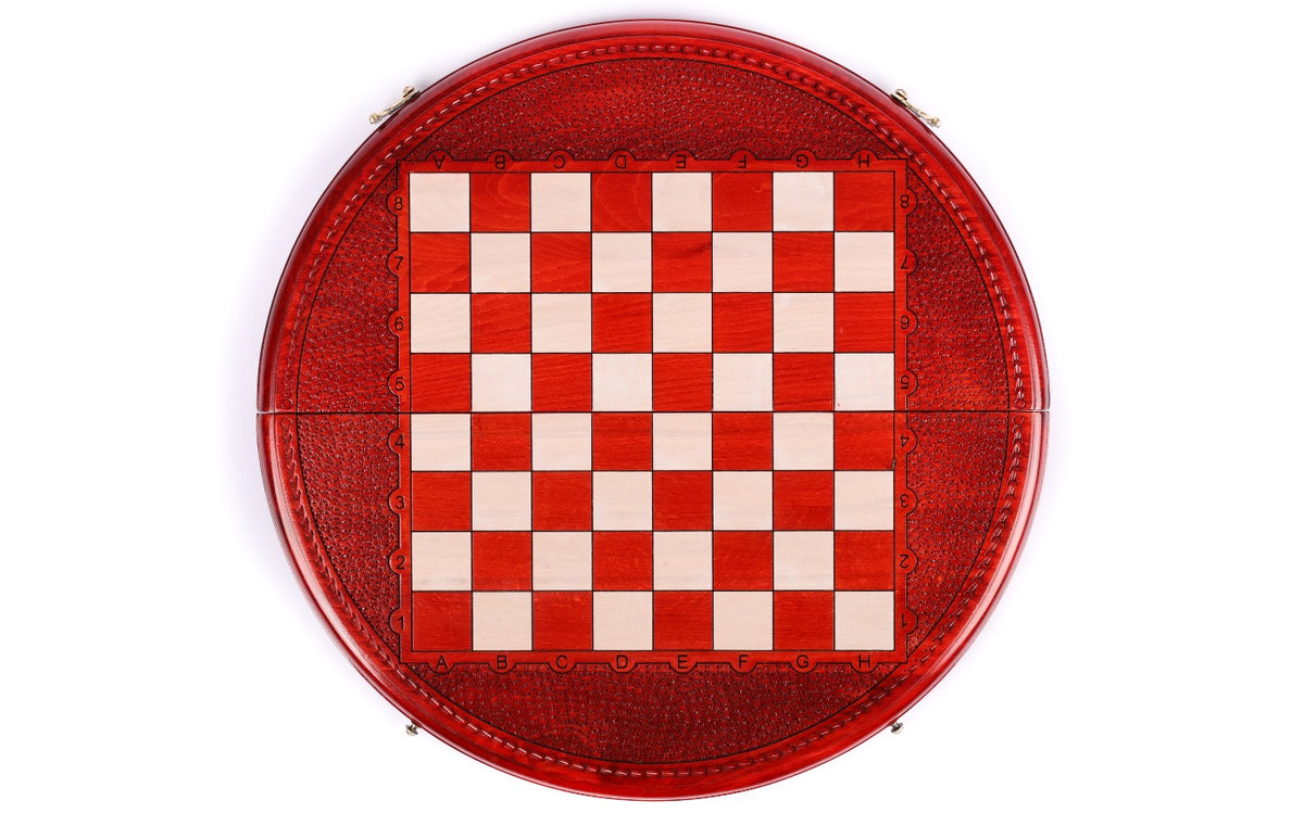 Top-down view of the round wooden chess board with red and cream squares and carved rim