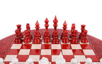 Red hand-carved chess pieces on the round board, white pieces in the foreground
